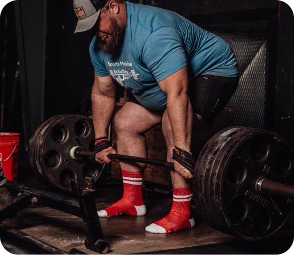 Athlete wearing red Squid Socks while lifting a barbell.