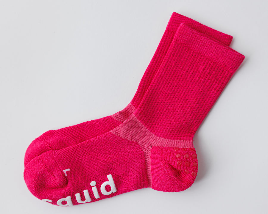 Electric Pink crew grip socks laid flat, showing the ribbed cuffs, heel grip dots, and white bottom grips. By Squid Socks.