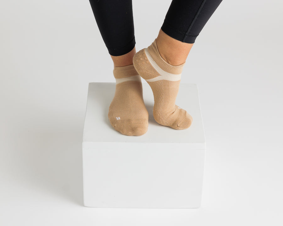 Tan ankle grip socks worn with black leggings on a display block. By Squid Socks.