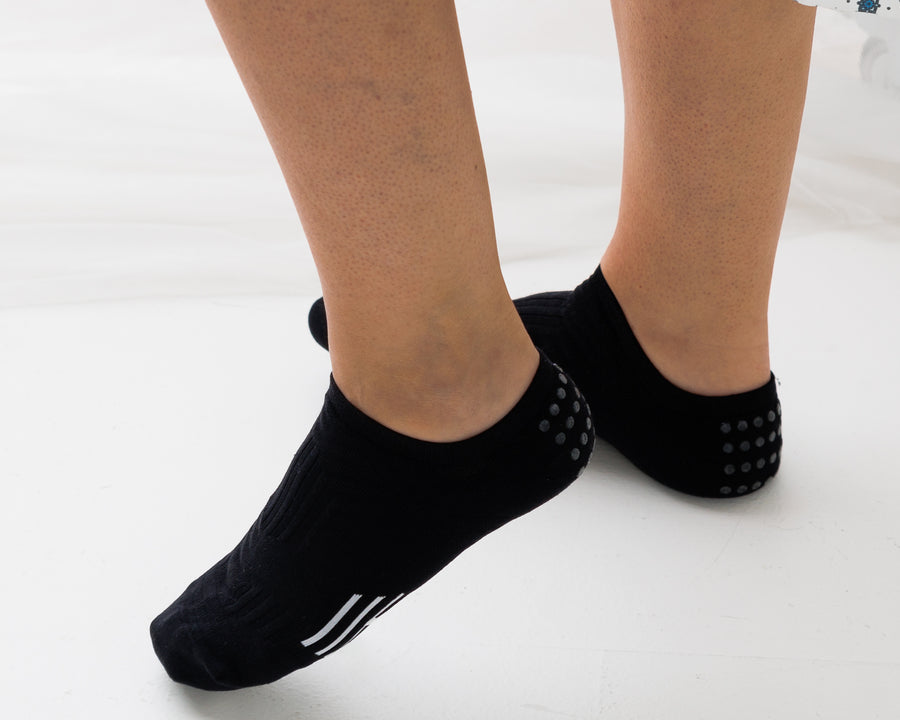 Black no-show grip socks worn on both feet, showing side and rear views. By Squid Socks.
