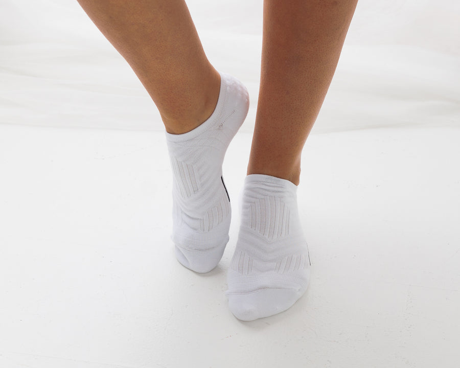 White no-show grip socks worn on both feet with one heel raised. By Squid Socks.
