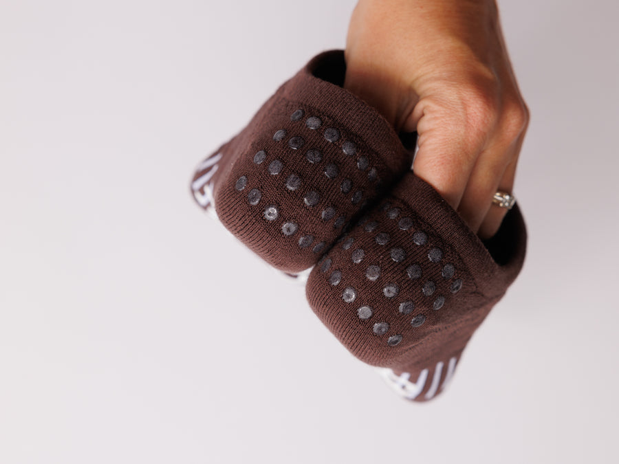 Hand holding brown no-show socks to show the grip dots on both heels. By Squid Socks.