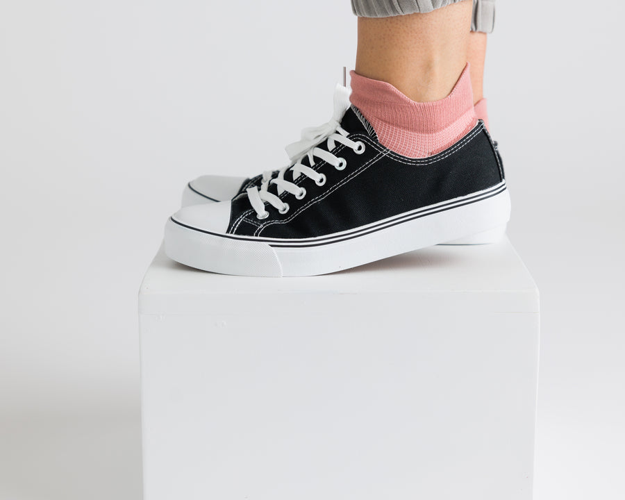 Light pink ankle grip sock worn with a black canvas sneaker, showing the raised heel tab. By Squid Socks.