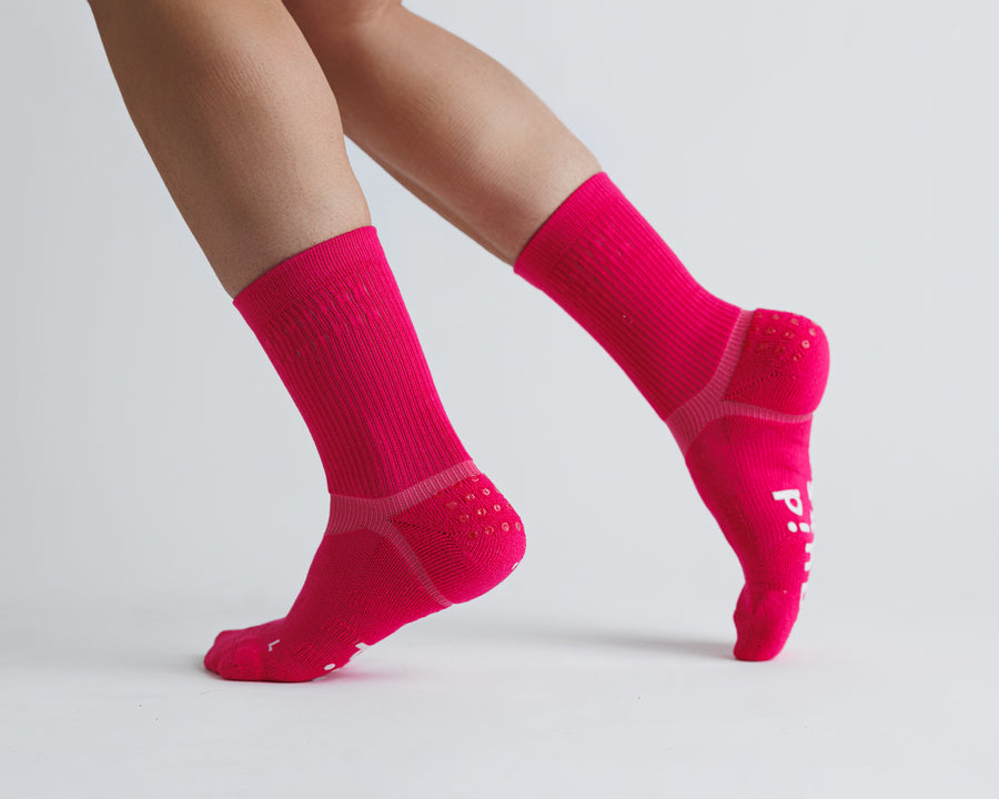 Electric Pink crew grip socks worn with heels raised, showing side views. By Squid Socks.