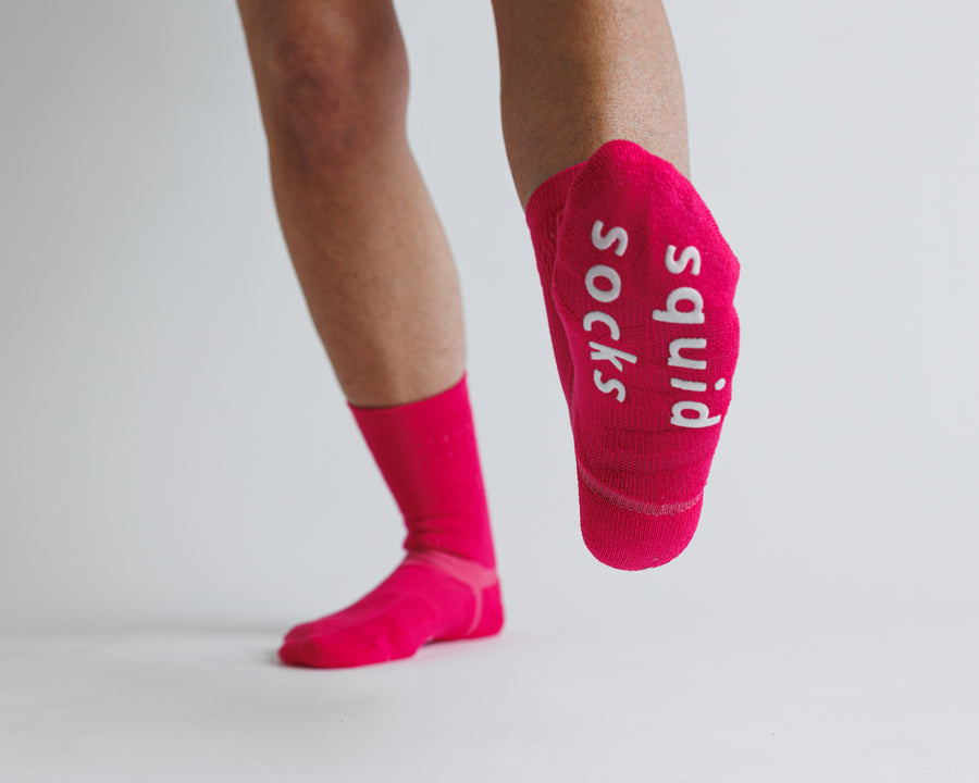 Electric Pink crew grip socks with one sole raised to show white bottom grips. By Squid Socks.