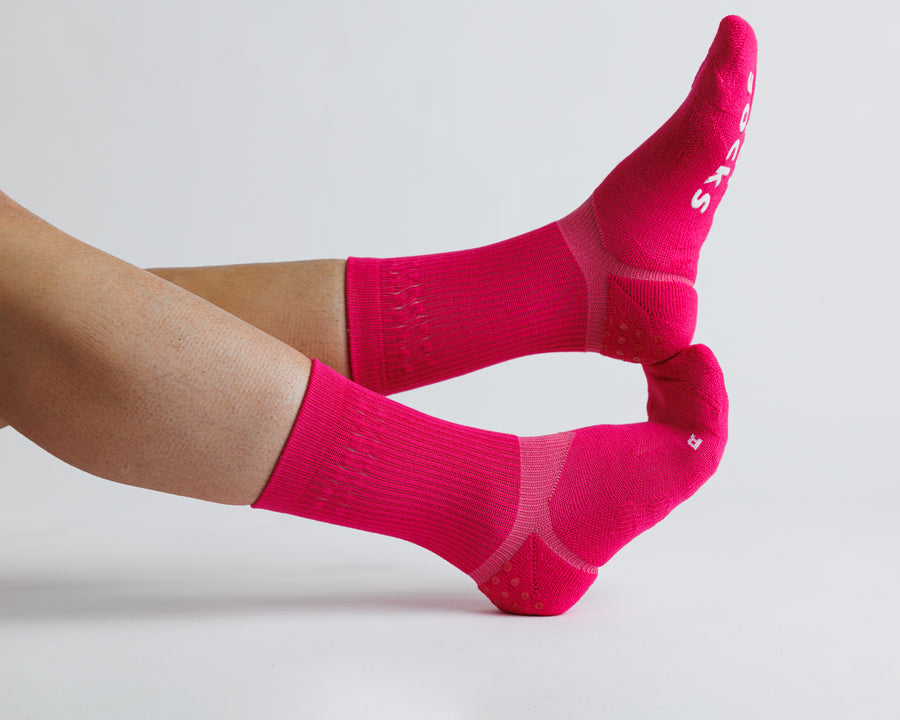 Electric Pink crew grip socks worn with legs extended, showing side views. By Squid Socks.