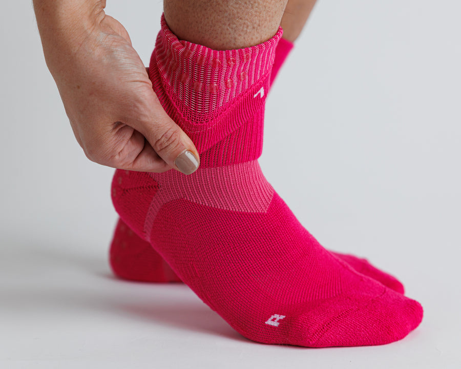 Person pulling back the cuff of an Electric Pink crew grip sock. By Squid Socks.