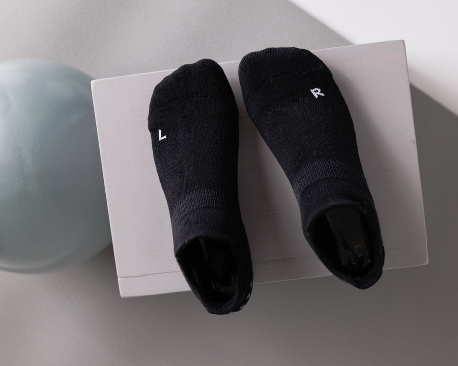 Black ankle grip socks displayed from above with left and right markings visible. By Squid Socks.