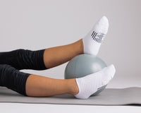 Thumbnail for White no-show grip socks worn during a mat exercise with a small exercise ball. By Squid Socks.