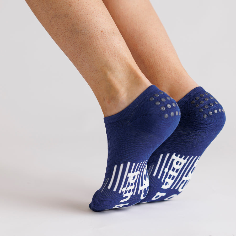 Navy no-show grip socks worn with heels raised, showing sole and heel grip details. By Squid Socks.