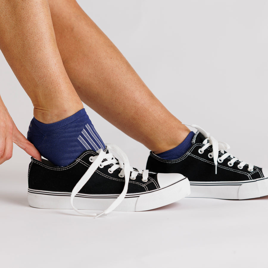 Navy no-show grip socks worn with black canvas sneakers. By Squid Socks.