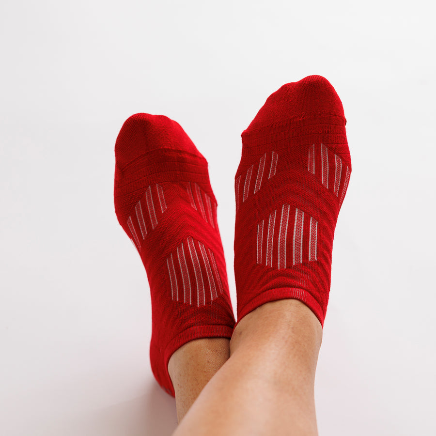 Red no-show grip socks worn on both feet, viewed from above. By Squid Socks.