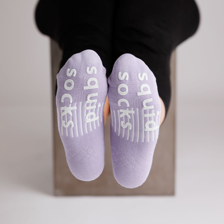 Lavender no-show grip socks viewed from the soles, showing white bottom grips. By Squid Socks.