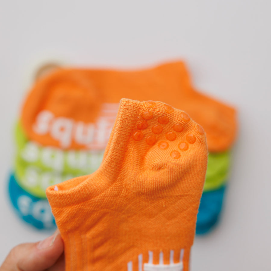 Close-up of an orange no-show sock showing grip dots inside the heel. By Squid Socks.