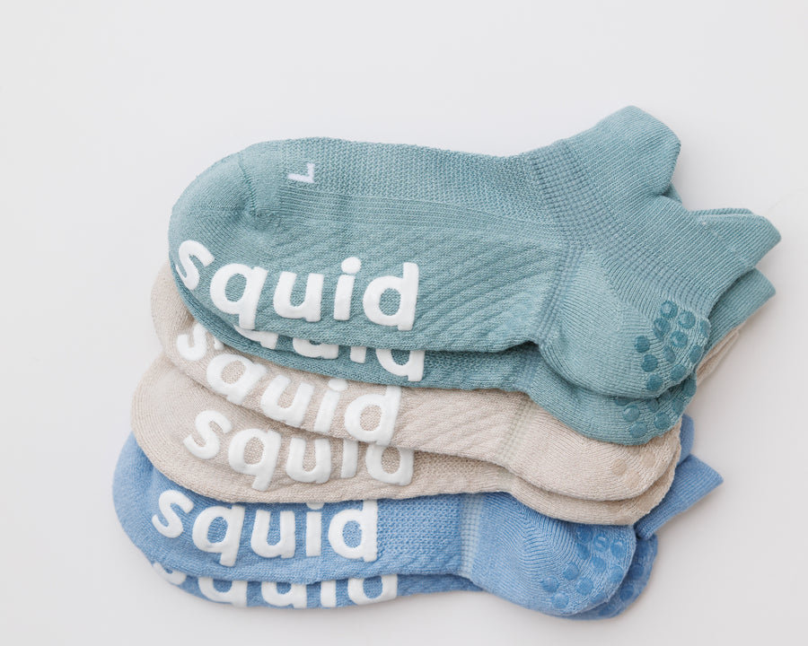 Seaside ankle grip socks in teal, cream, and blue, stacked with heel and bottom grips visible. By Squid Socks.