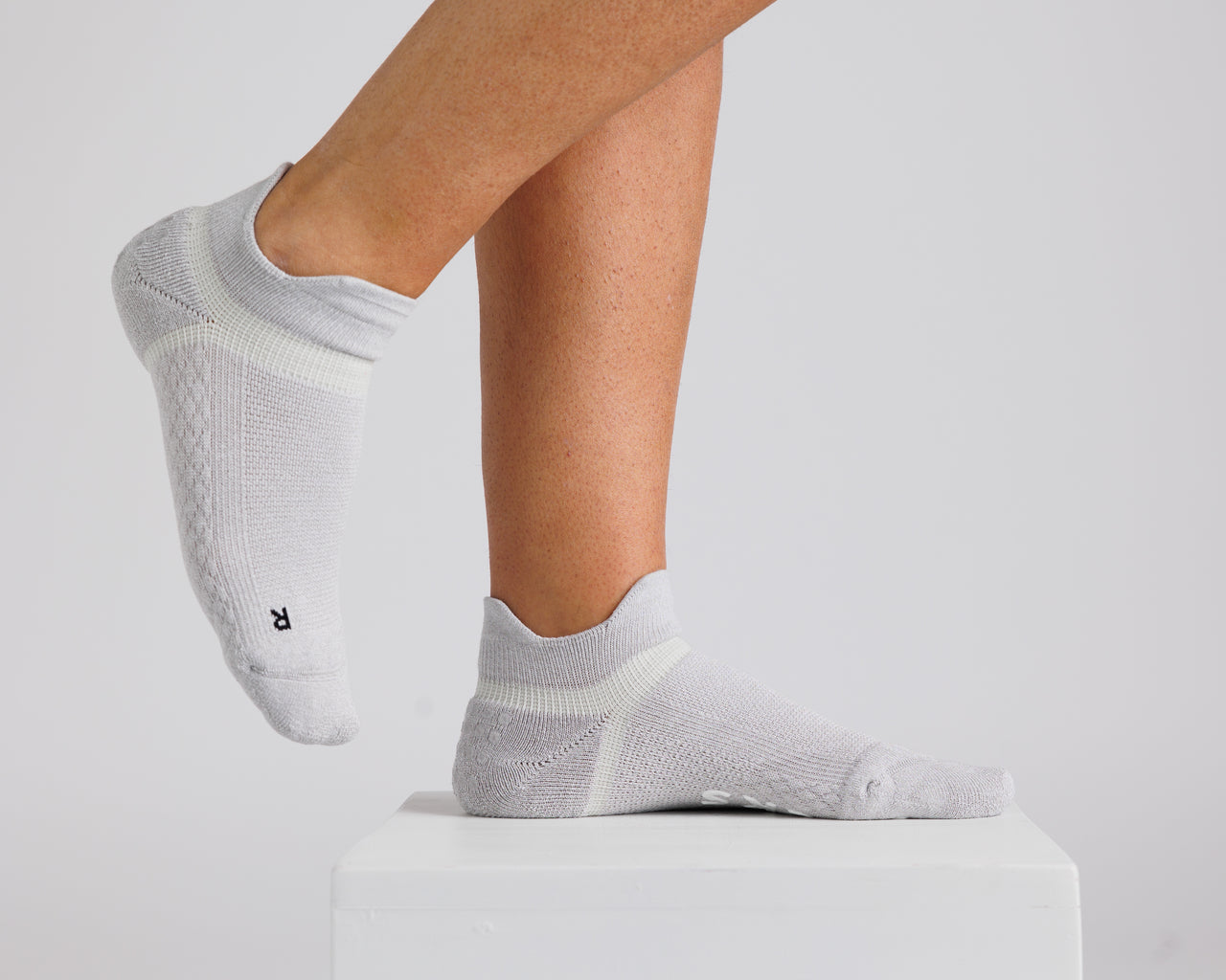 Gray ankle grip socks worn on a display block, showing side and top views. By Squid Socks.