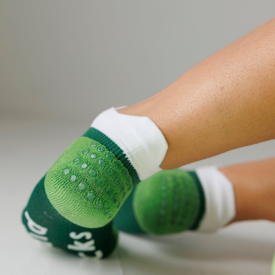 Close-up of green ankle pickleball grip socks worn on both feet, showing grip dots on the heels. By Squid Socks.