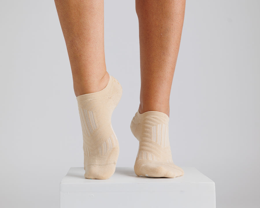 Cream no-show grip socks worn on both feet with one heel raised. By Squid Socks.