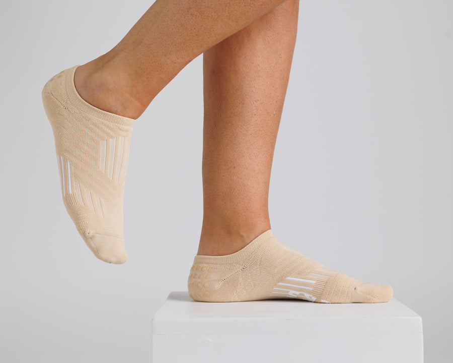 Cream no-show grip socks worn on a display block, showing side and top views. By Squid Socks.