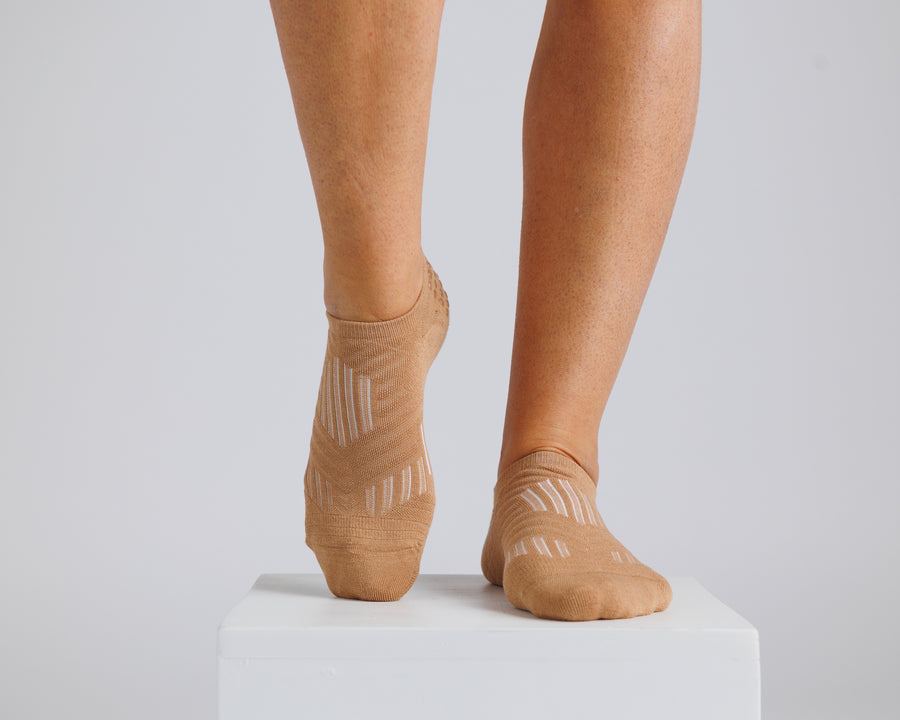 Brown no-show grip socks worn on both feet, showing the knitted top panels. By Squid Socks.