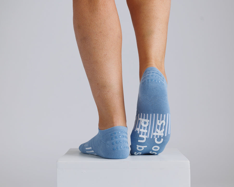 Blue no-show grip socks worn on a display block, with one sole raised to show the bottom grips. By Squid Socks.