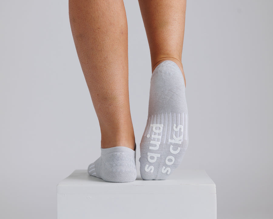 Gray no-show grip socks with one sole raised to show white bottom grips. By Squid Socks.