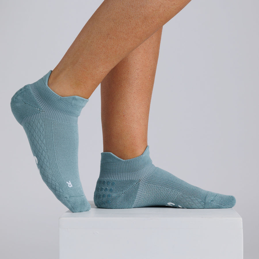 Teal ankle grip socks worn on a display block, showing side and top views. By Squid Socks.