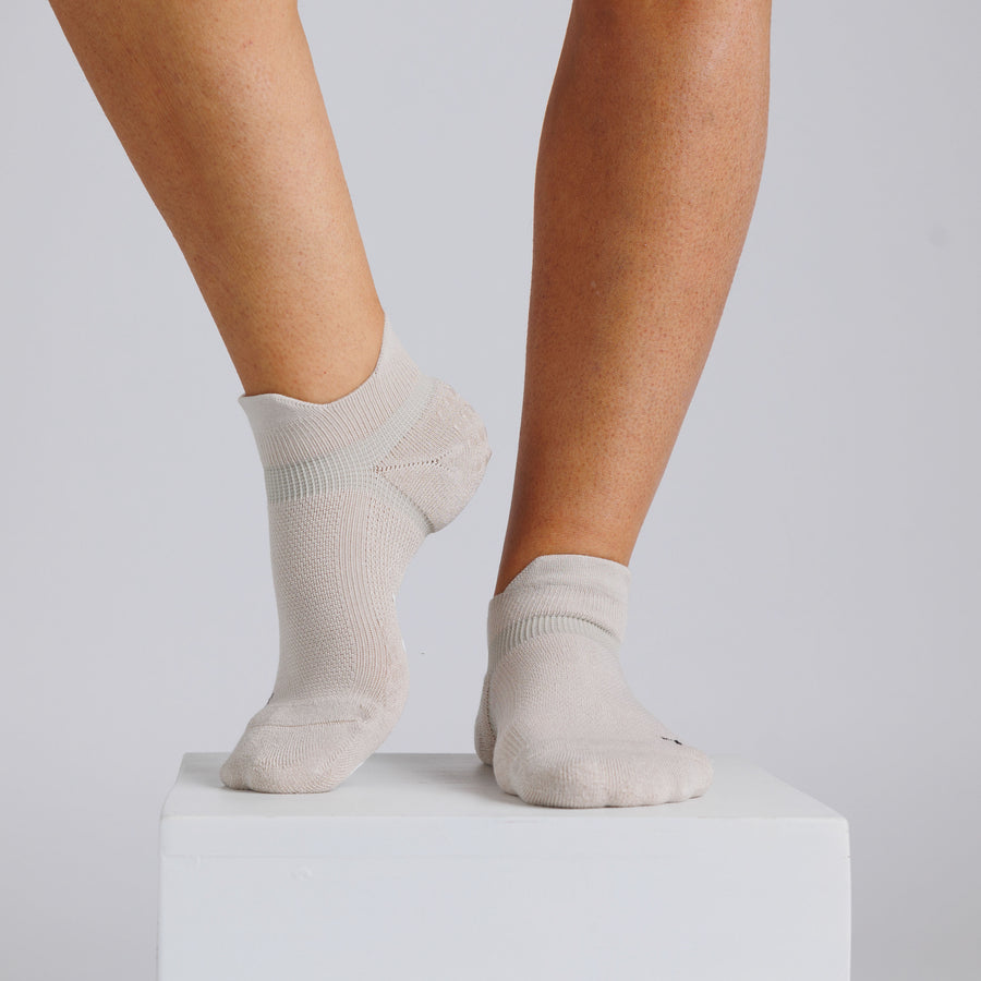 Cream ankle grip socks worn on a display block with one heel raised. By Squid Socks.