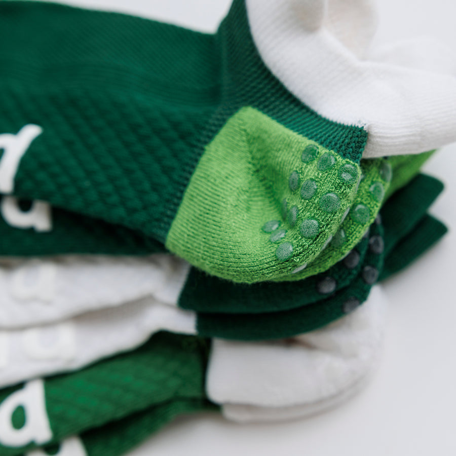 Close-up of stacked Pickle Pack ankle pickleball socks showing grip dots on a green heel panel. By Squid Socks.