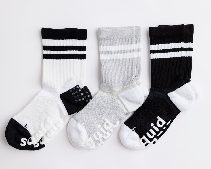 Retro crew grip socks in white, gray, and black, arranged flat with striped cuffs visible. By Squid Socks.
