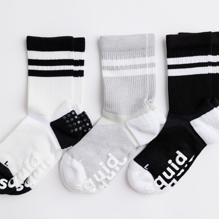 White, gray, and black Retro crew grip socks arranged side by side with striped cuffs visible. By Squid Socks.