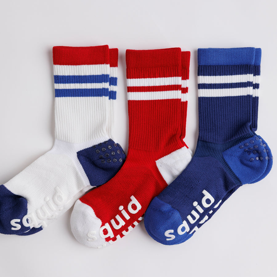White, red, and navy All-American crew grip socks arranged side by side. By Squid Socks.
