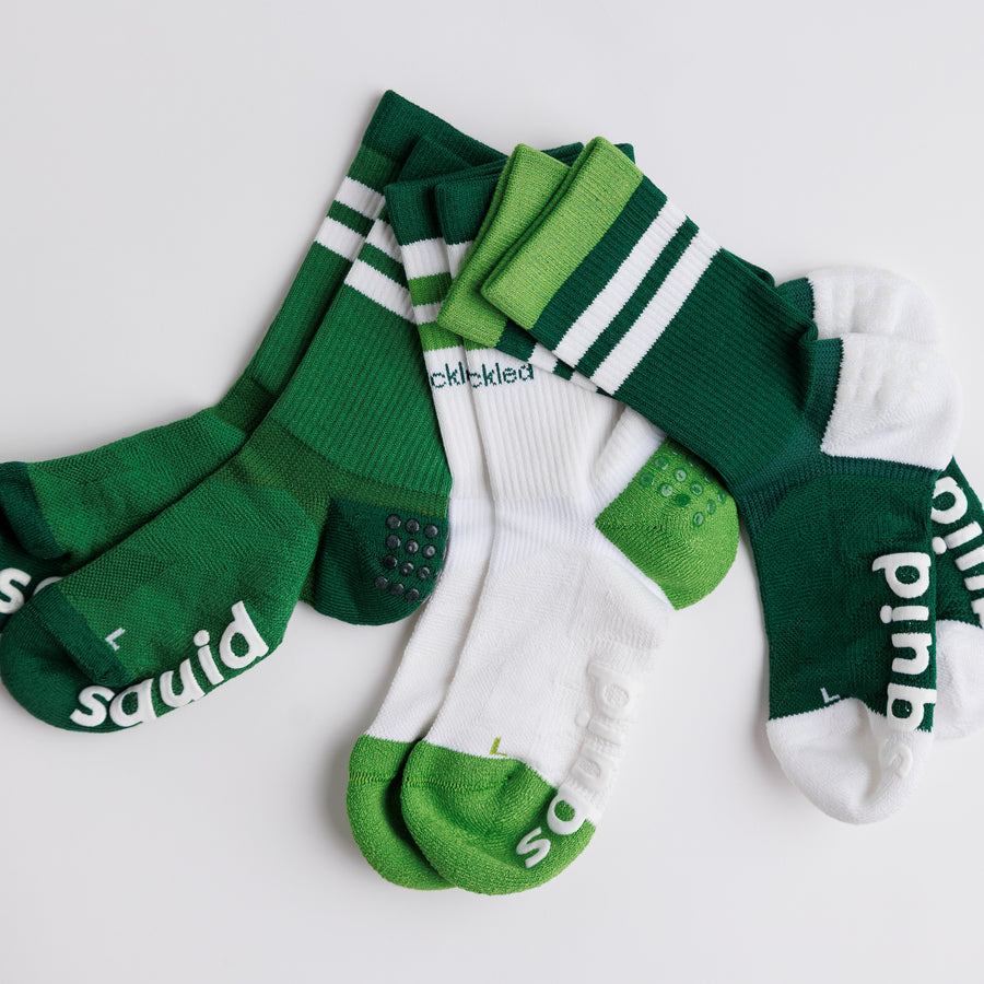 Green and white Pickle Pack crew pickleball grip socks arranged to show striped cuffs, heel panels, and bottom grips. By Squid Socks.
