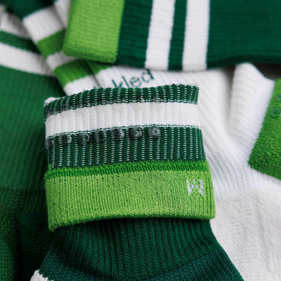 Close-up of a green striped crew pickleball sock cuff folded back to show interior grip dots and size marking. By Squid Socks.