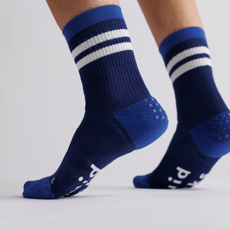 Navy crew grip socks with white stripes worn with heels raised. By Squid Socks.