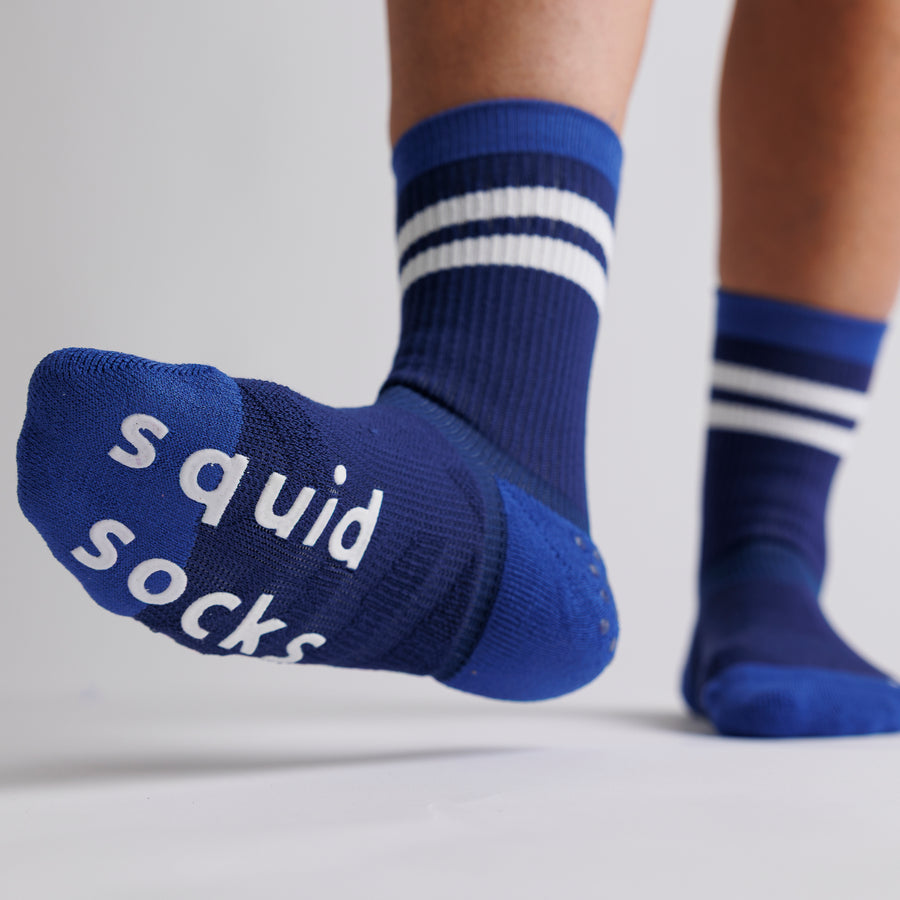 Navy All-American crew grip sock with one sole raised to show white bottom grips. By Squid Socks.