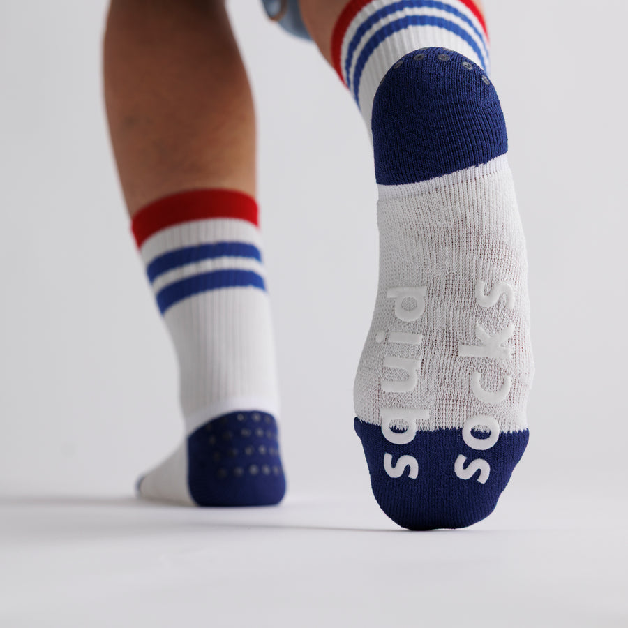 White All-American crew socks with one sole raised to show bottom grips and a navy toe panel. By Squid Socks.