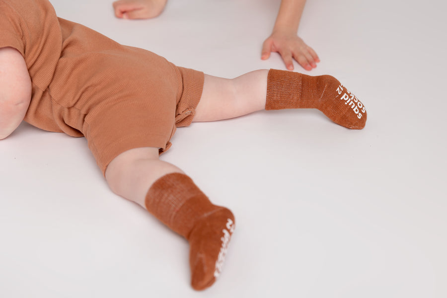 Cypress kids socks: baby lying down in cognac socks. Squid Socks, the brand seen on Shark Tank.