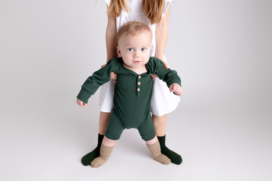Cypress kids socks: baby being supported while standing in dark green socks. Squid Socks, the brand seen on Shark Tank.