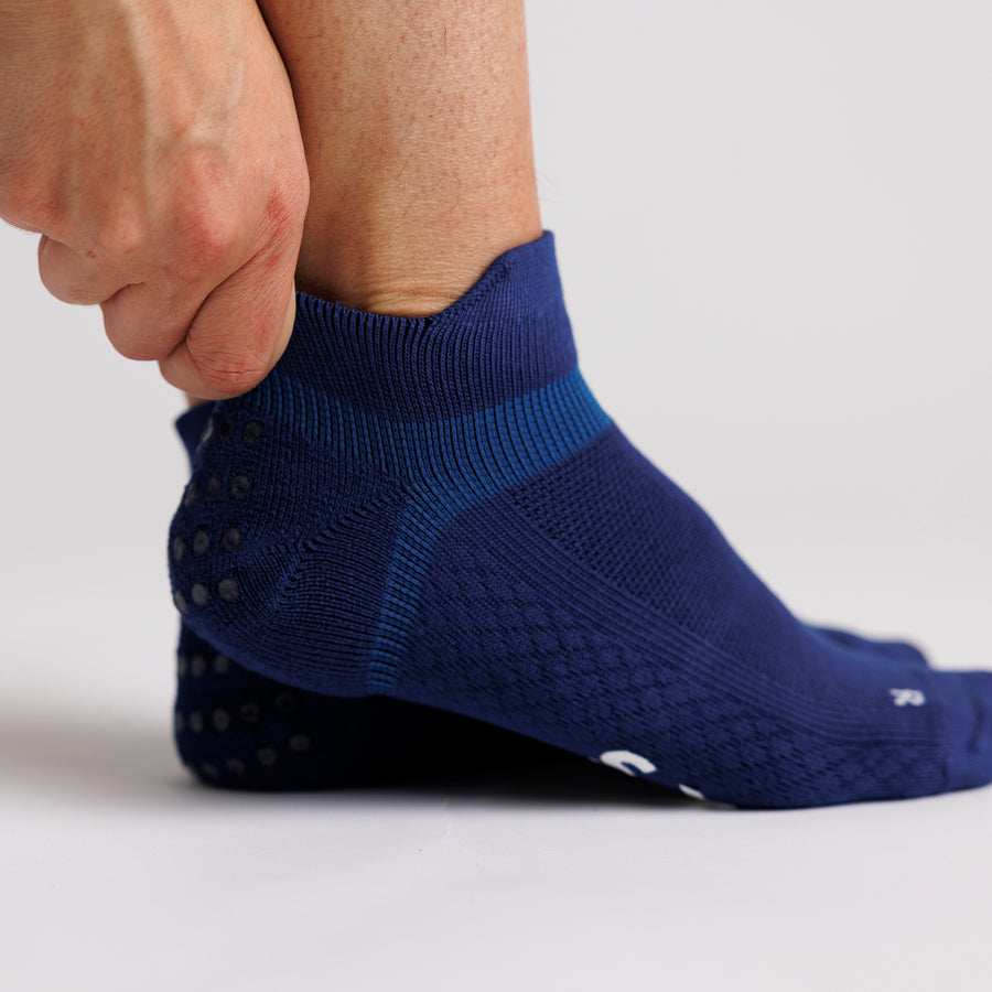 Person adjusting the cuff of a navy ankle grip sock. By Squid Socks.
