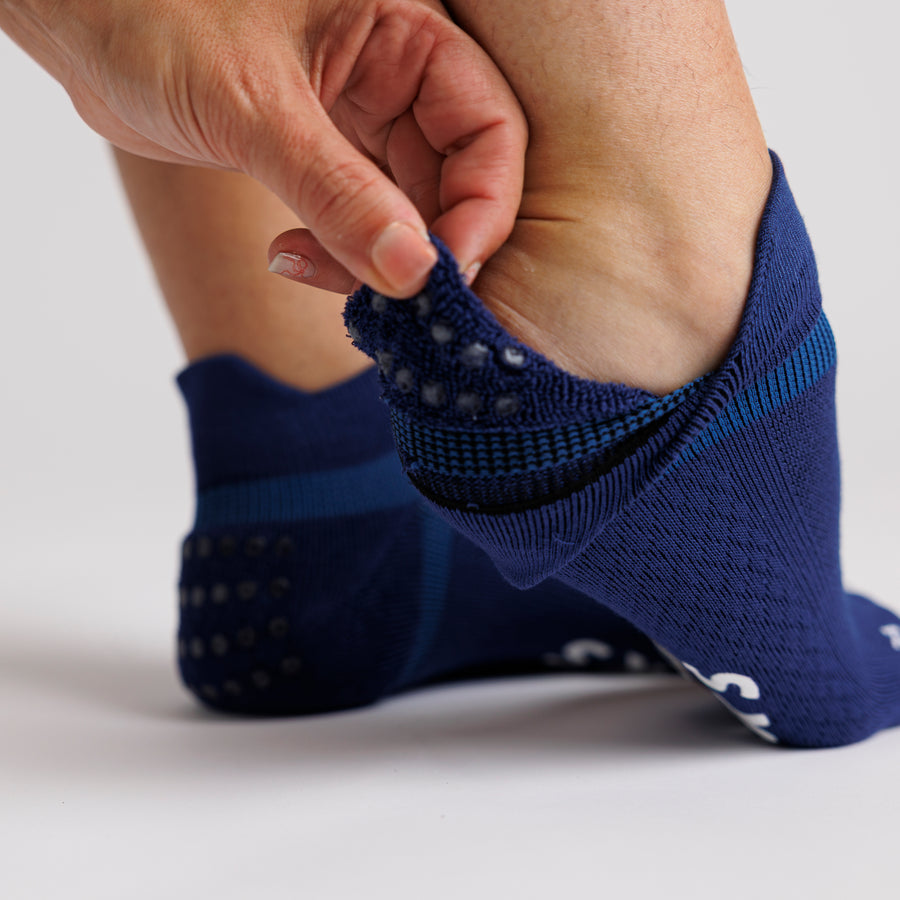 Close-up of a navy ankle sock pulled back to show grip dots inside the heel. By Squid Socks.