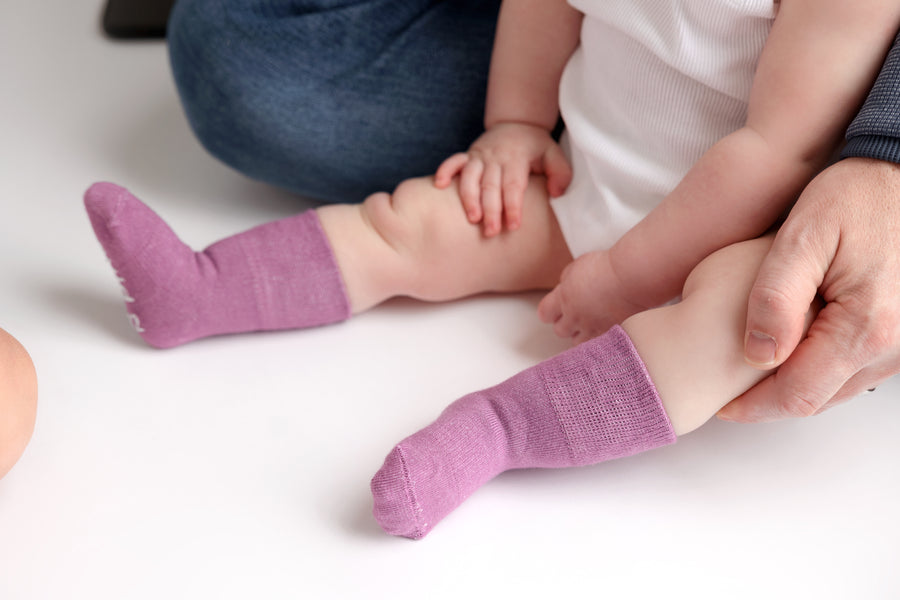 Orchid kids socks: adult supporting a baby's legs in lavender socks. Squid Socks, the brand seen on Shark Tank.