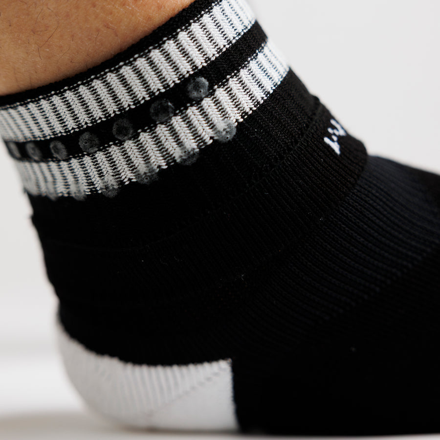 Close-up of a black crew sock cuff folded back to show the interior grip dots. By Squid Socks.