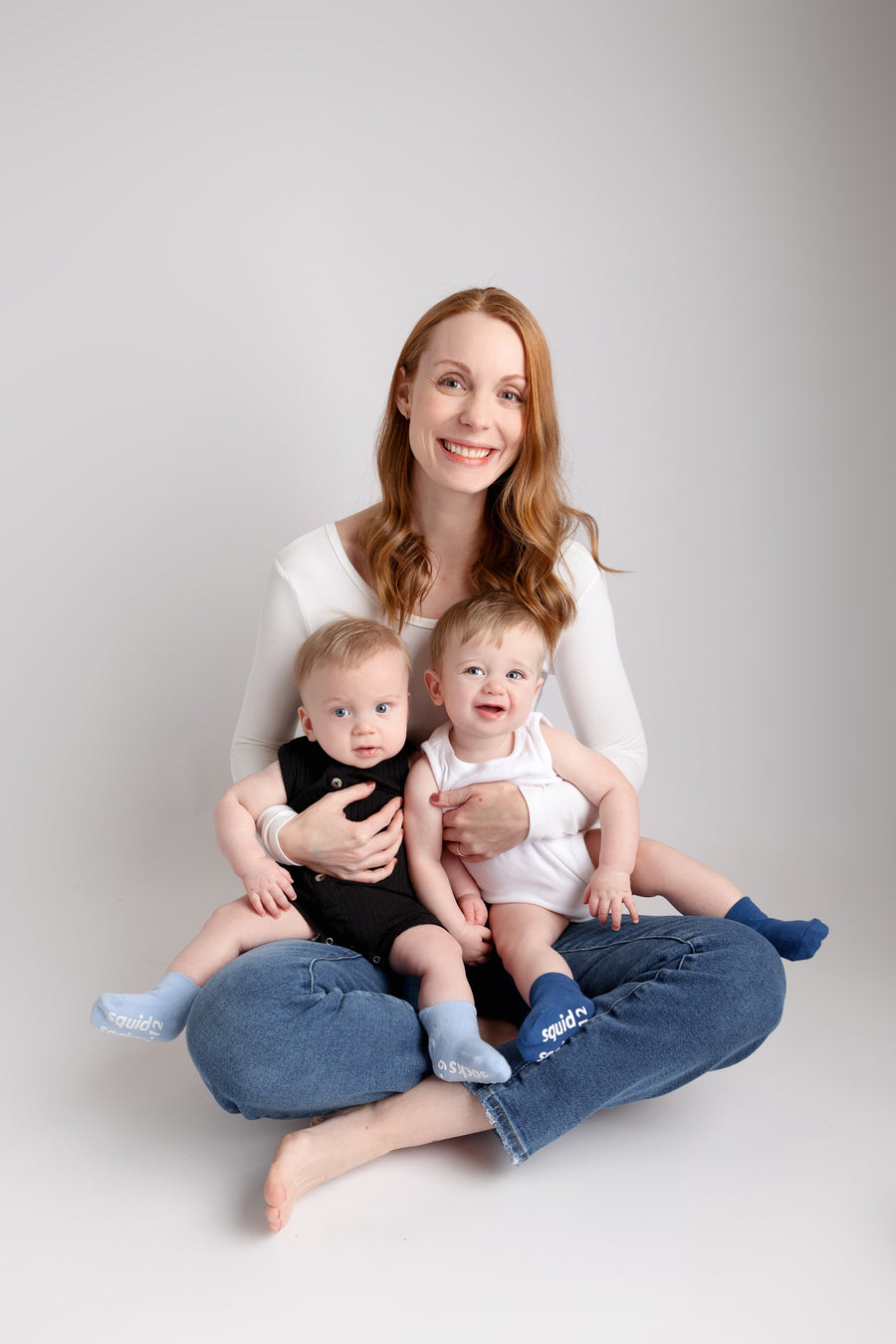 Chaney ankle socks: adult seated holding two babies wearing blue ankle socks. Squid Socks, the brand seen on Shark Tank.