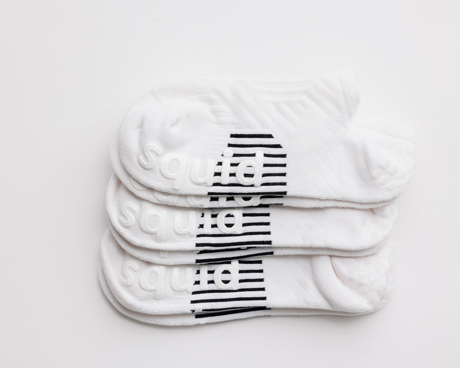 No-Brainer white no-show grip socks stacked with black bottom grips visible. By Squid Socks.