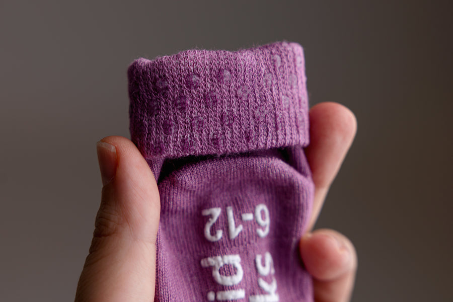 Orchid kids socks: hand holding a bright lavender sock with folded cuff. Squid Socks, the brand seen on Shark Tank.