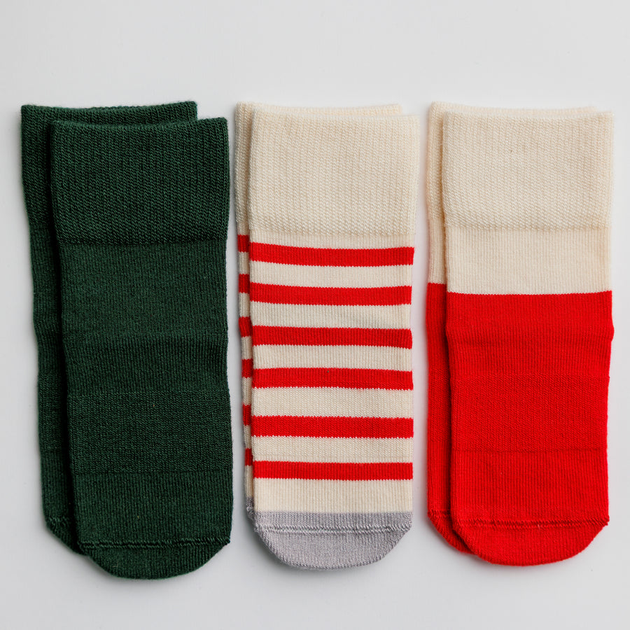 Caroler baby and kids grip socks in dark green, red and cream Christmas patterns.