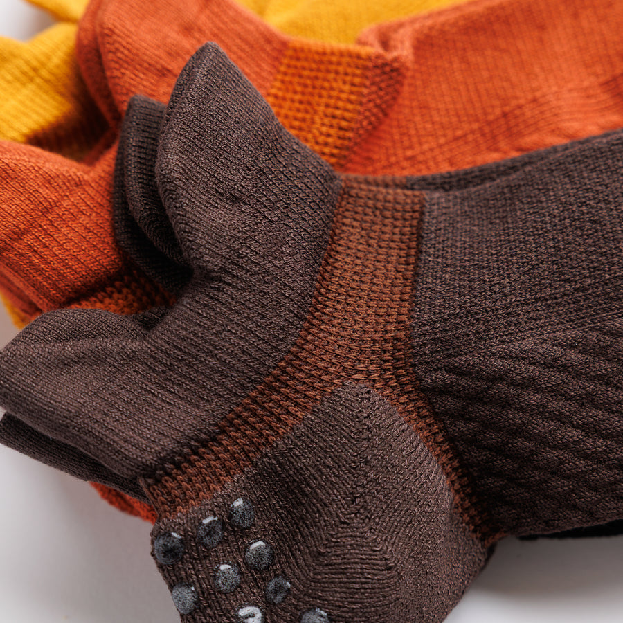 Close-up of brown and rust orange ankle socks showing the heel tabs and knit panels. By Squid Socks.