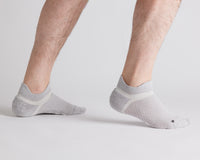 Thumbnail for Gray ankle grip socks worn with heels raised, showing side views and heel tabs. By Squid Socks.