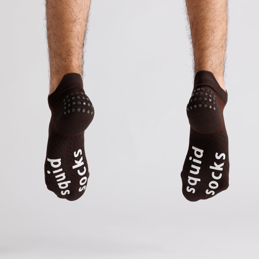 Brown ankle grip socks with both soles facing the camera, showing white bottom grips. By Squid Socks.